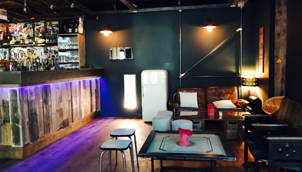 Intérieur de bar lounge tamisé avec comptoir, assises et tables basses, pour illustrer un cadre d’afterwork.