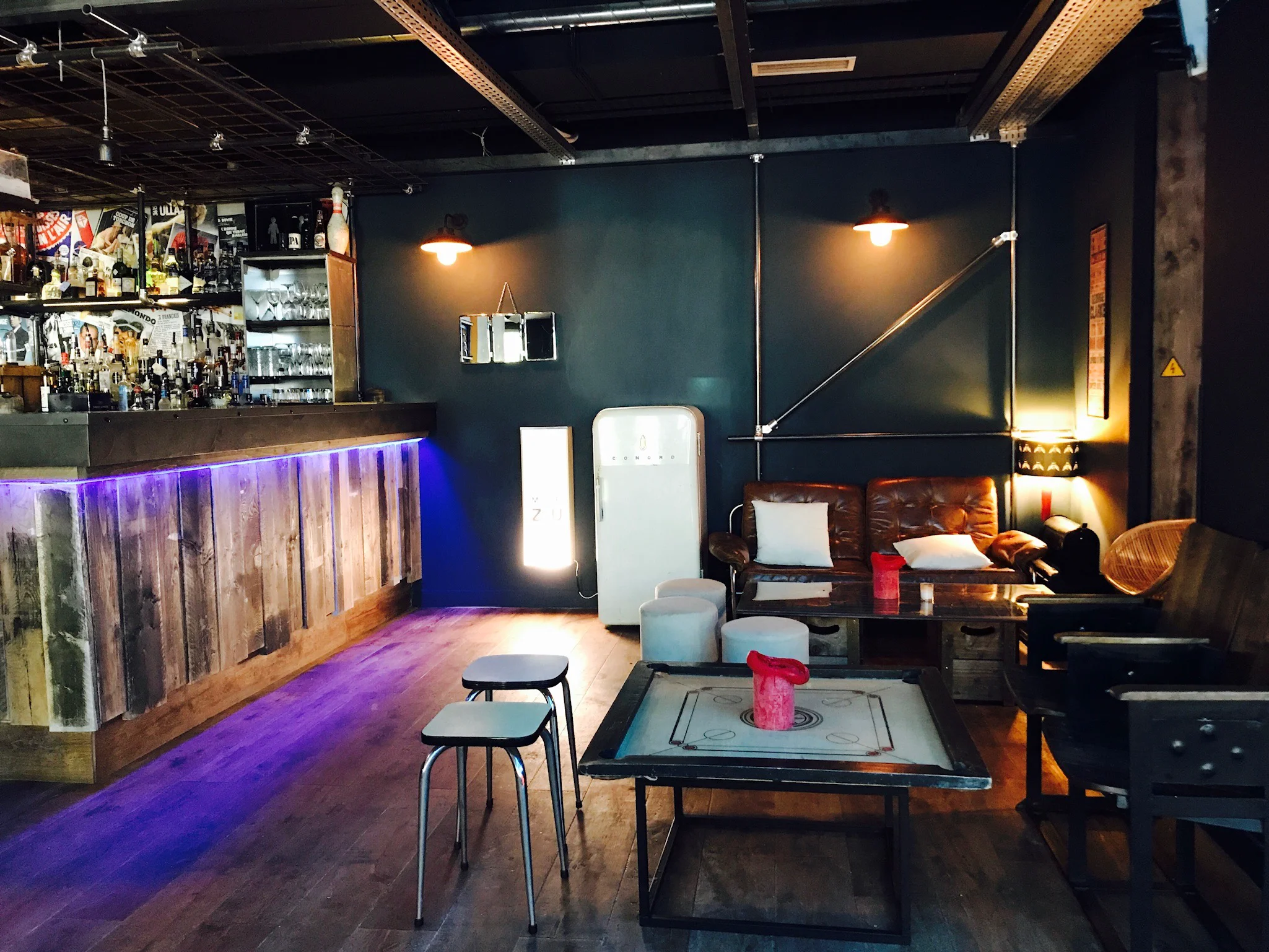 Intérieur de bar lounge tamisé avec comptoir, assises et tables basses, pour illustrer un cadre d’afterwork.