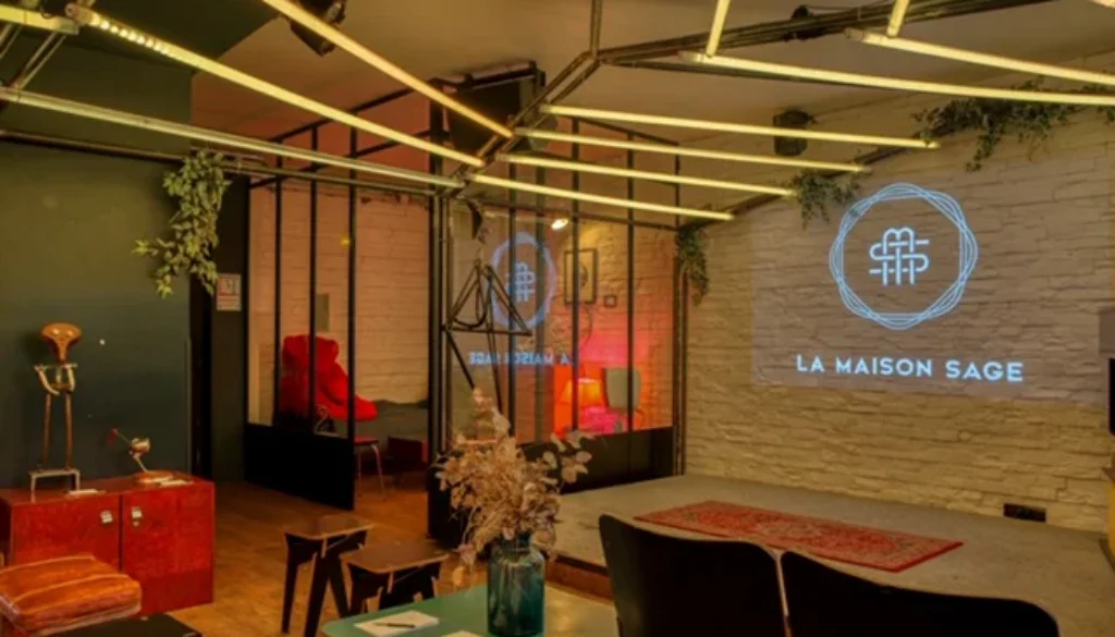 Espace lounge chaleureux avec tables, assises, plantes et mur de pierre.