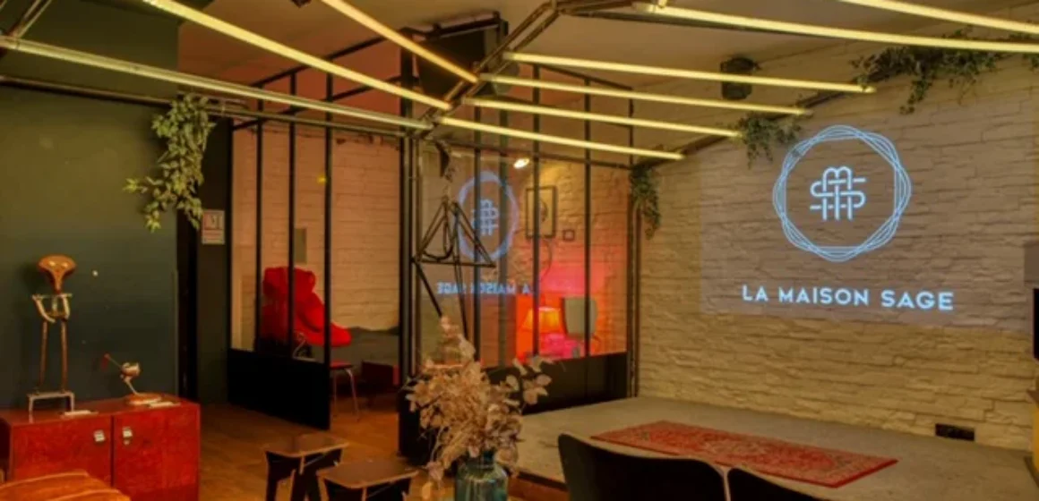 Espace lounge chaleureux avec tables, assises, plantes et mur de pierre.
