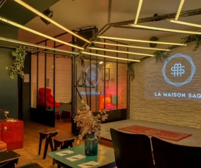Espace lounge chaleureux avec tables, assises, plantes et mur de pierre.
