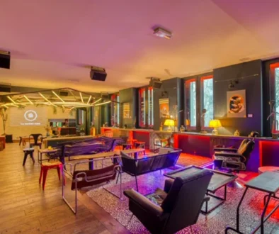 Espace lounge intérieur avec canapés, fauteuils, tables et grand écran